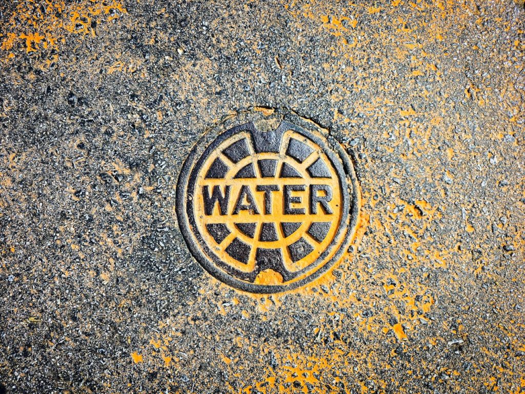 close-up-of-urban-water-utility-cover-art-31731604 Colorful water utility cover on street pavement blends art with functionality.
